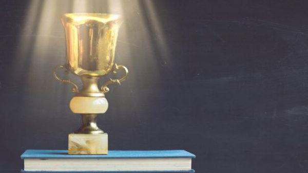 golden trophy on pile of books in front of blackboard